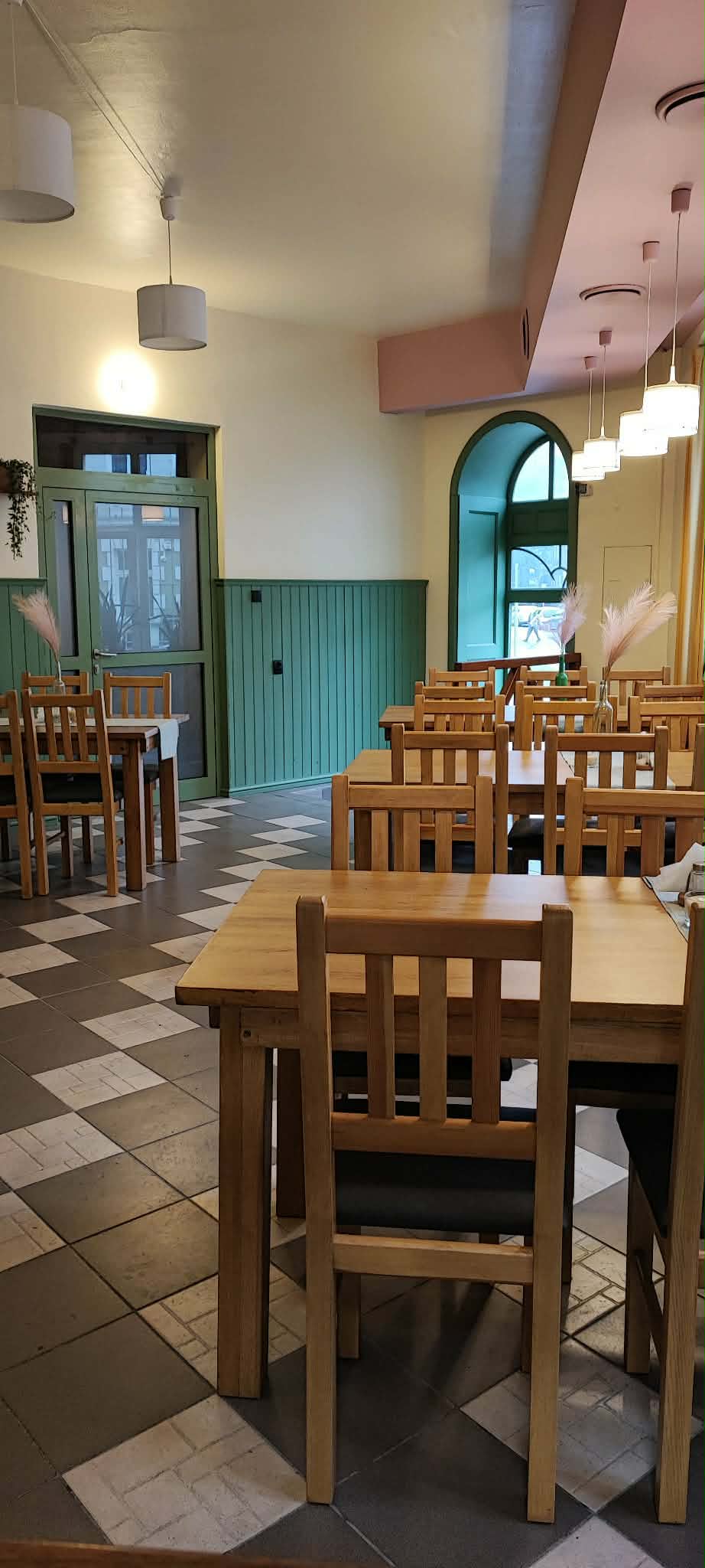 Sala bistro z drewnianymi stołami i zieloną boazerią